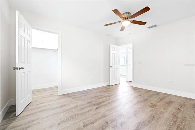an empty room with wooden floor and ceiling fan