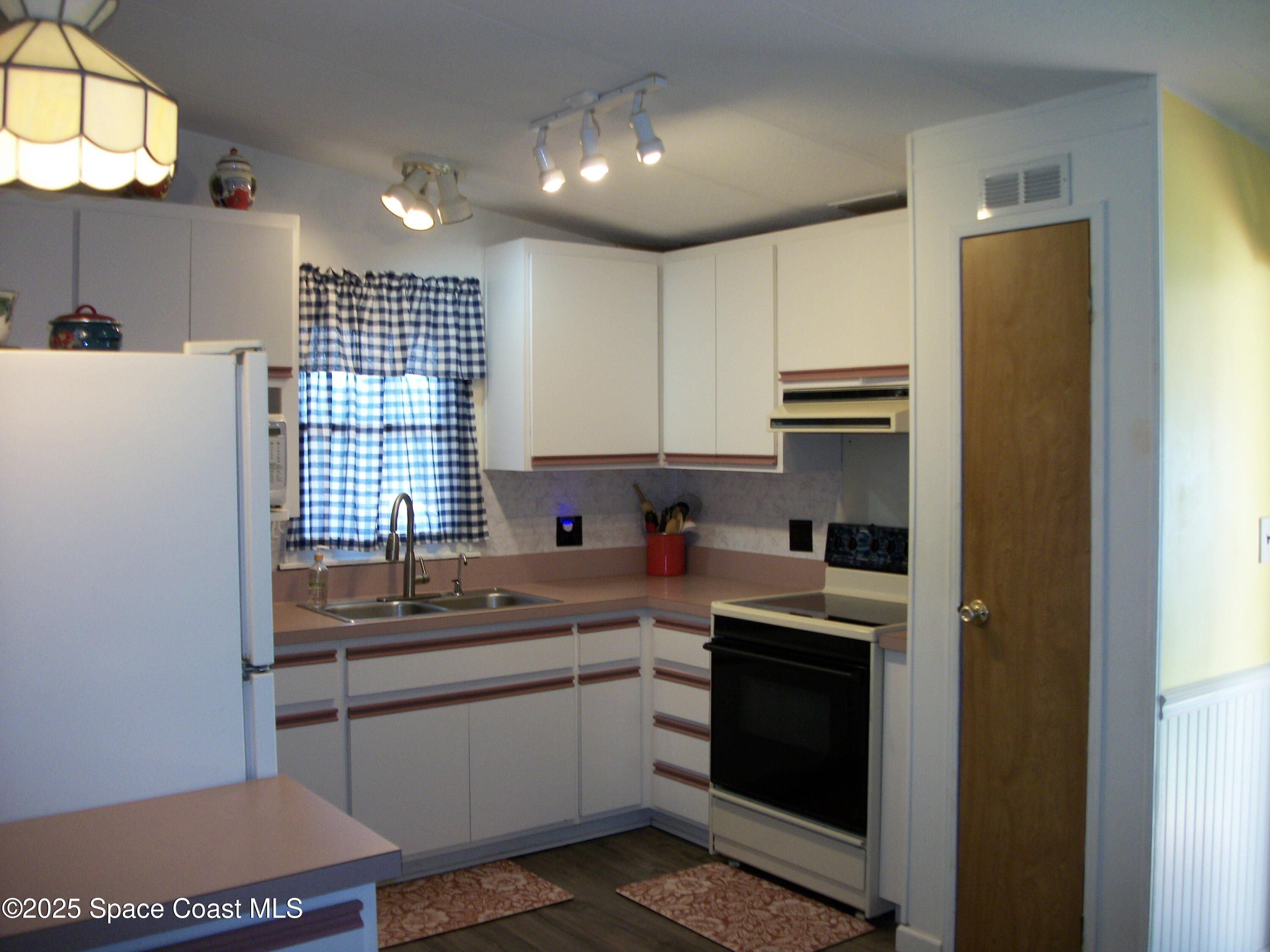 1972 Mango Street Northeast Palm Bay, FL 32905 - Photo 4 of 41 a kitchen with a sink cabinets stainless steel appliances and a window
