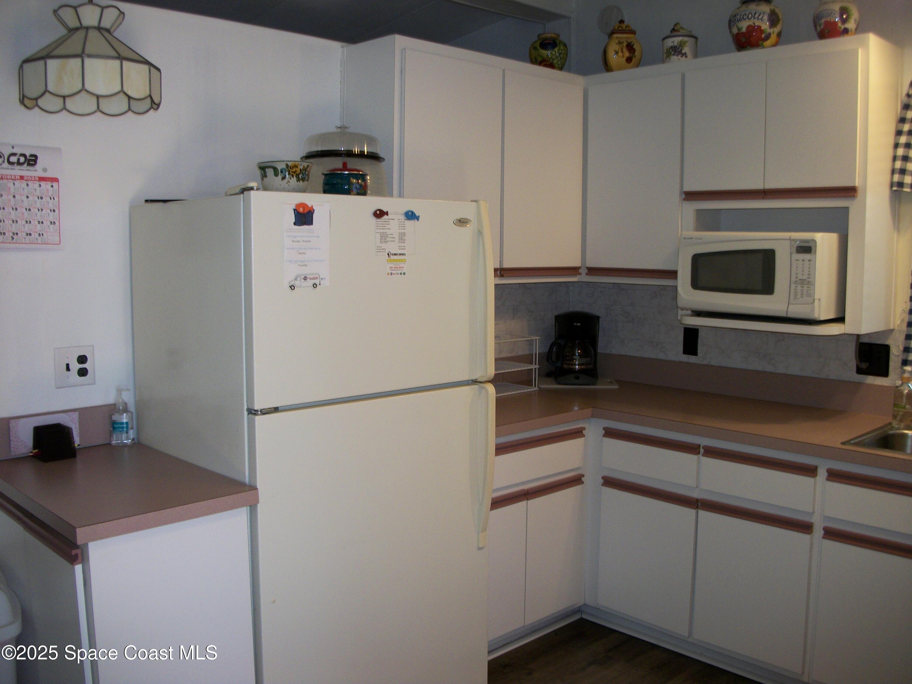 1972 Mango Street Northeast Palm Bay, FL 32905 - Photo 5 of 41 a white kitchen with sink a refrigerator and cabinets
