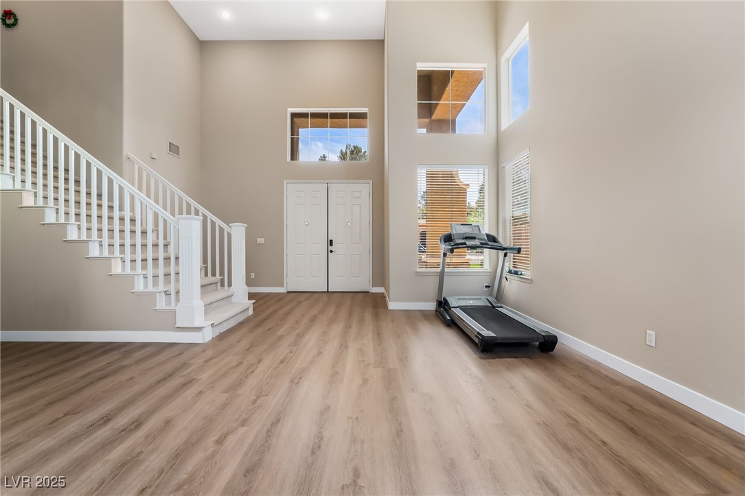 Foyer entrance featuring stairway, a towering ceiling, wood finished floors, and plenty of natural light