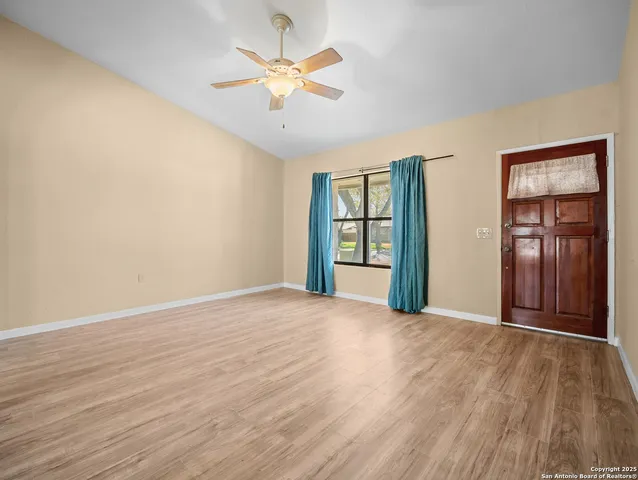 a view of an empty room with a window and wooden floor