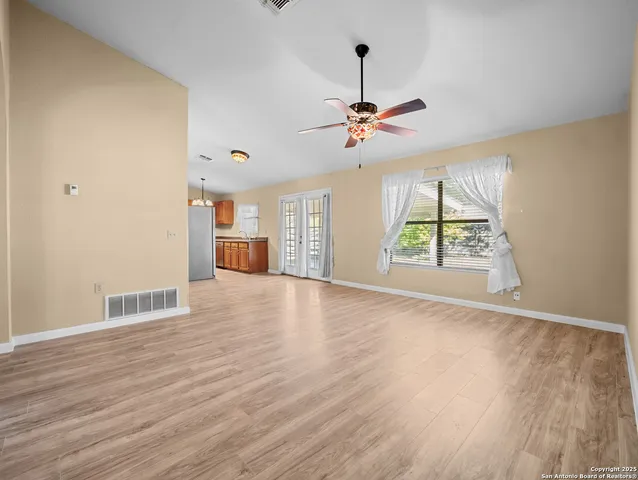a view of an empty room with a window and wooden floor