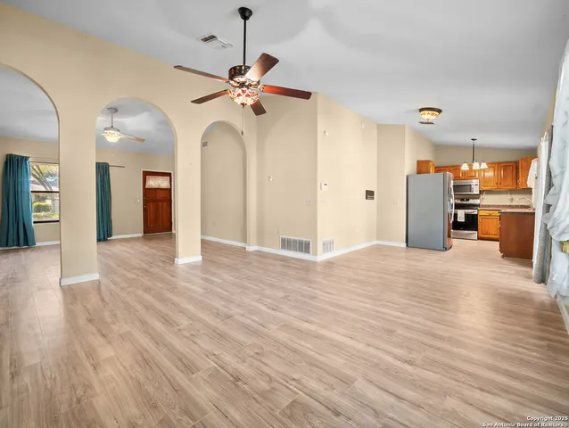 an empty room with wooden floor chandelier and glass door