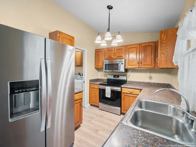 a kitchen with stainless steel appliances granite countertop a refrigerator a sink dishwasher a oven with a dining table and chairs