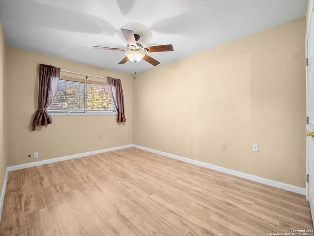 an empty room with wooden floor chandelier fan and windows