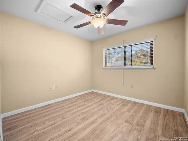 a view of an empty room with window and a chandelier fan
