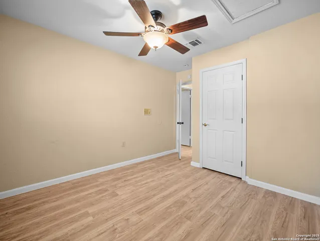 an empty room with wooden floor and a ceiling fan