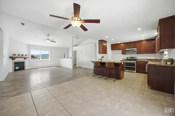 a kitchen with stainless steel appliances kitchen island granite countertop a refrigerator and a stove top oven