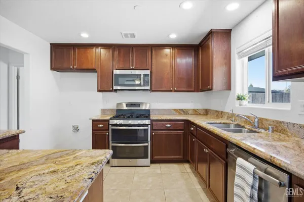 a kitchen with stainless steel appliances granite countertop wooden cabinets a stove top oven a sink and dishwasher