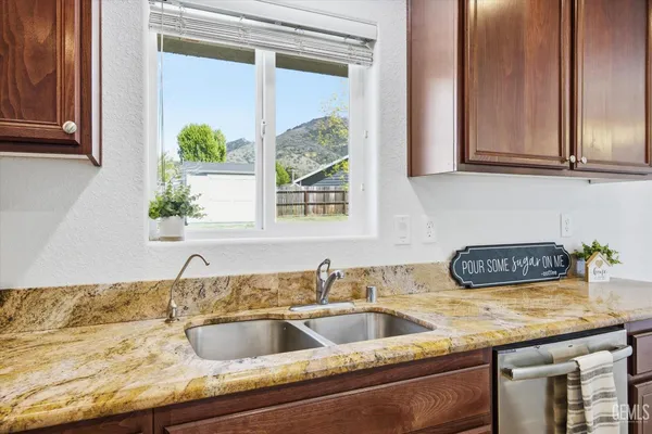 a kitchen with granite countertop a sink a counter space and cabinets