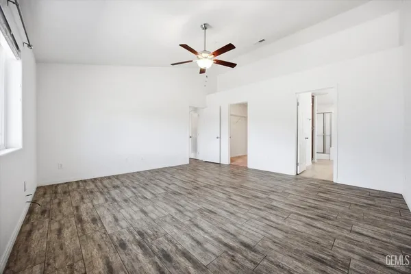 a view of empty room with wooden floor and ceiling fan