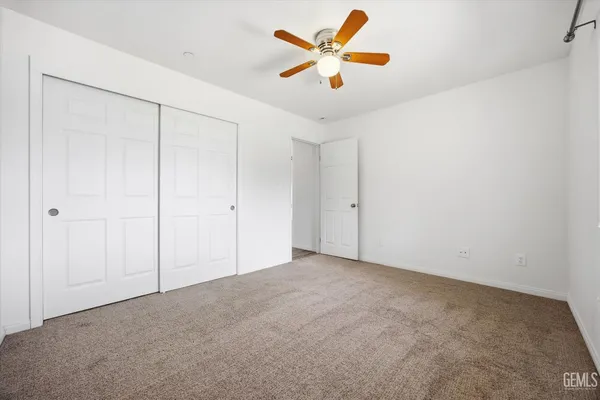 an empty room with closet and a ceiling fan