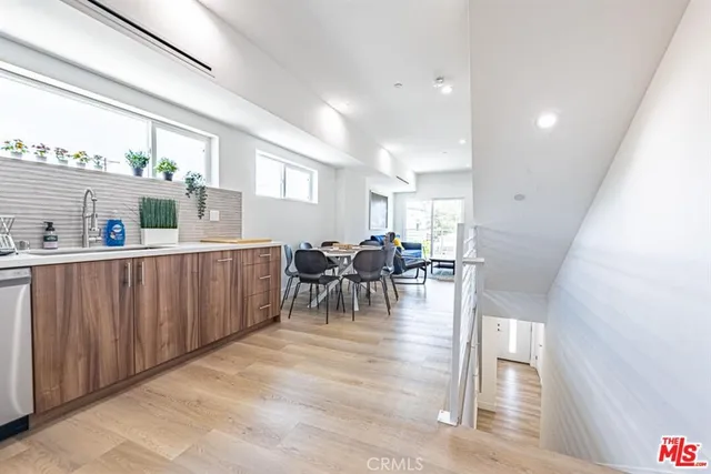 a dining hall with stainless steel appliances a dining table and chairs with wooden floor