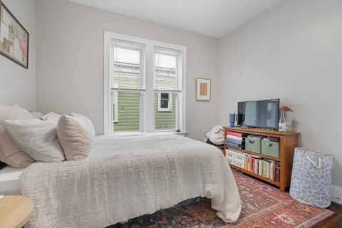 a bedroom with a bed a table and chair with window