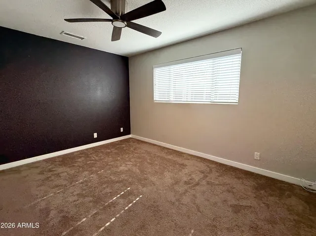 an empty room with windows and fan