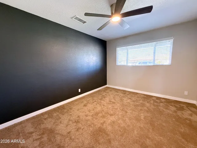 an empty room with a ceiling fan and a window