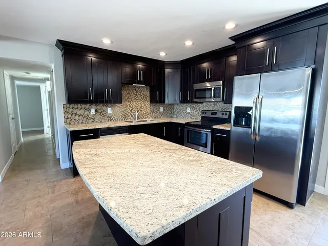 a kitchen with kitchen island granite countertop wooden cabinets and refrigerator