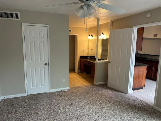 a view of a refrigerator in kitchen and an empty room
