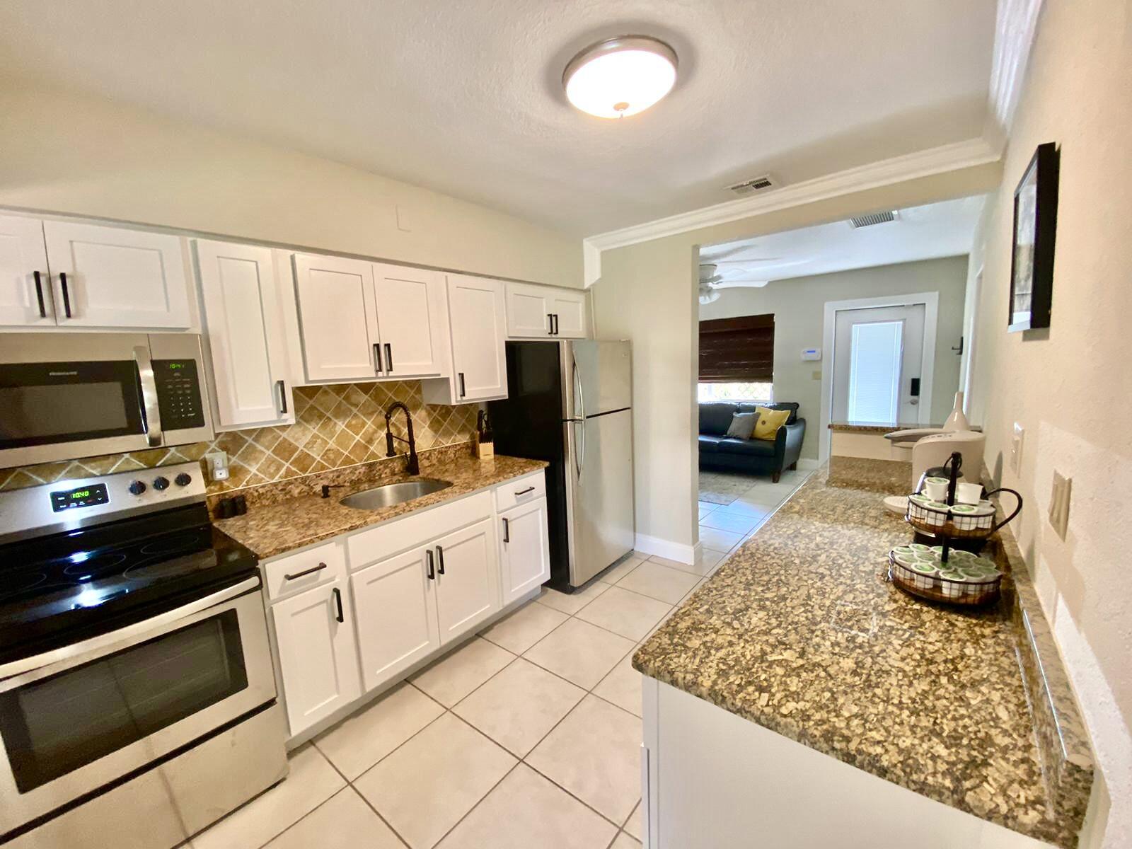 a kitchen with stainless steel appliances granite countertop a stove top oven a sink dishwasher and white cabinets
