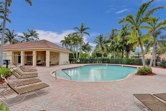 a view of swimming pool with lawn chairs and palm trees