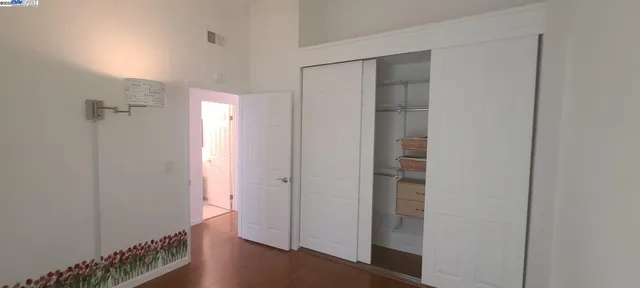 a view of a hallway with wooden floor and a bathroom