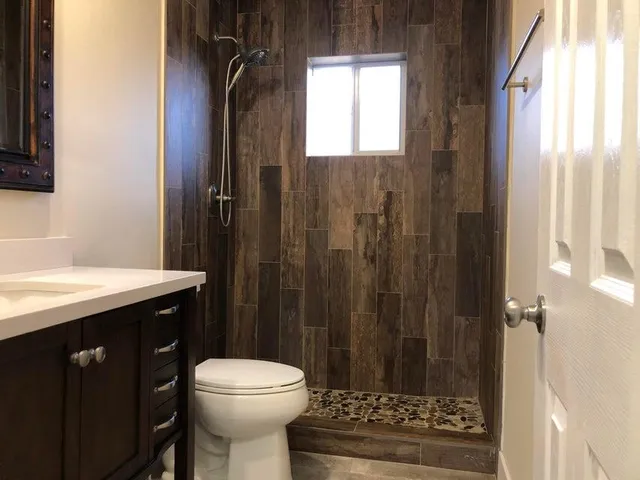 a bathroom with a sink a toilet a mirror and shower