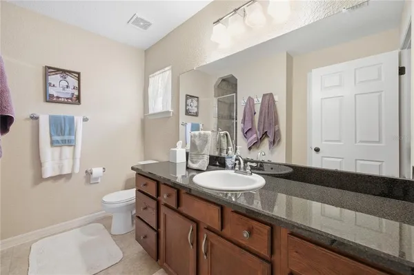 a bathroom with a granite countertop toilet sink and mirror