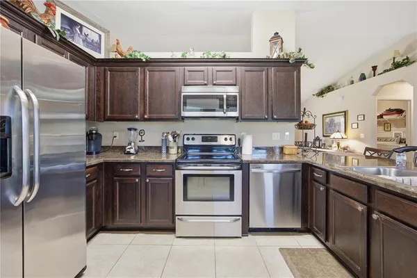 a kitchen with stainless steel appliances granite countertop a stove a sink and a microwave