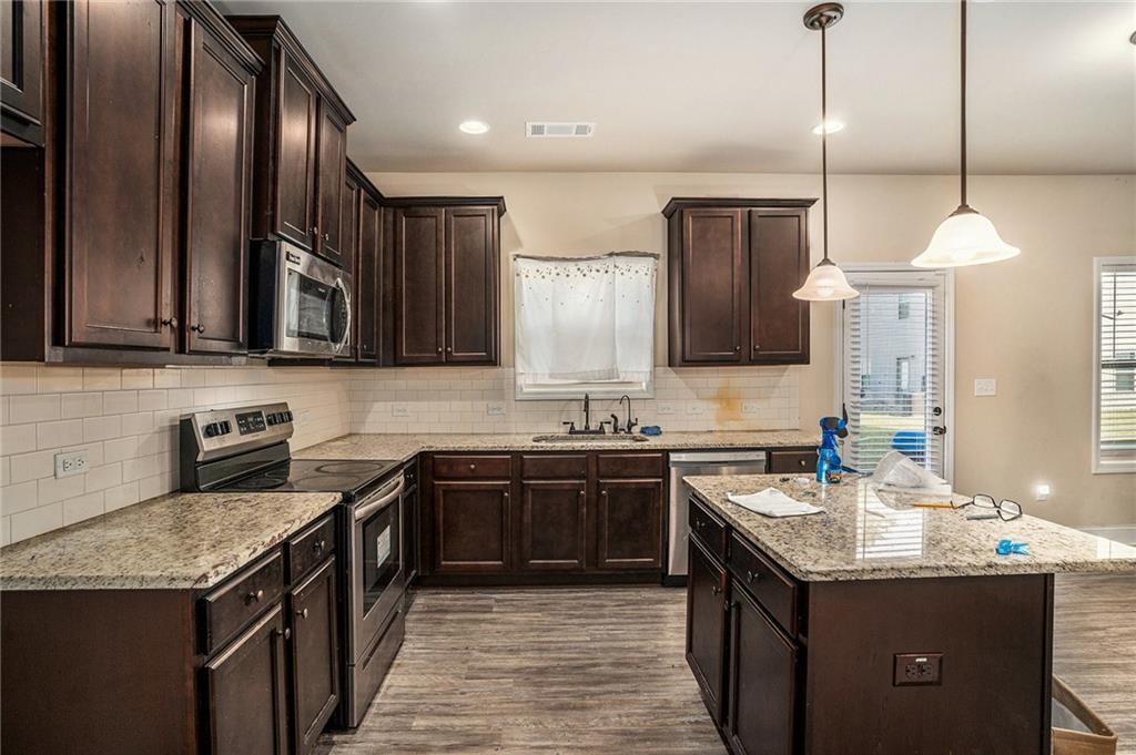2277 Church Street Hampton, GA 30228 - Photo 12 of 30 a kitchen with granite countertop stainless steel appliances a sink stove top oven and cabinets