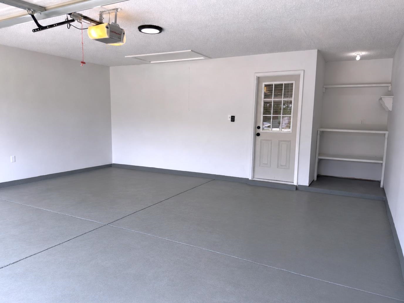 927 Cully Road Memphis, TN 38018 - Photo 25 of 33 Spacious garage featuring a durable gray epoxy floor, bright white walls, built-in shelving, and a side entry door with window panes