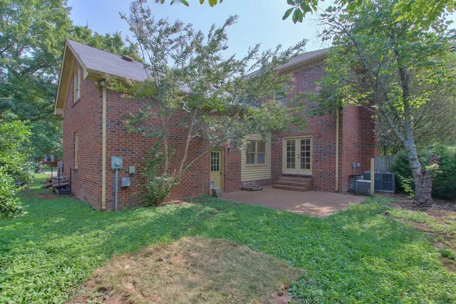 front view of a house with a yard and a large tree