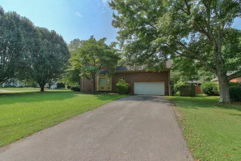 a front view of a house with a yard and trees