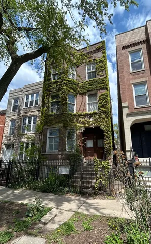 a view of a brick house with many windows next to a yard
