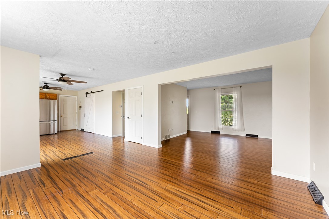 6272 Merwin Chase Road Brookfield, OH 44403 - Photo 5 of 38 Unfurnished living room featuring ceiling fan, a textured ceiling, and hardwood / wood-style flooring