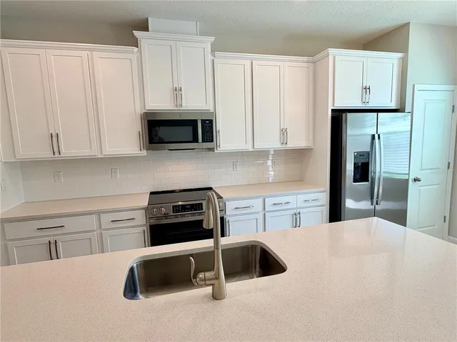 a kitchen with granite countertop a sink stove and refrigerator