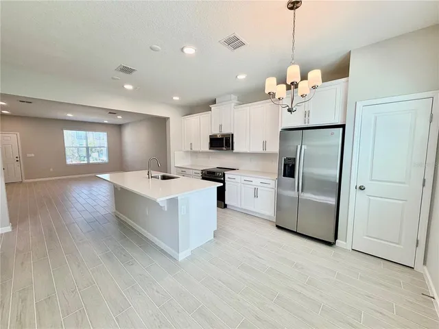 a large white kitchen with stainless steel appliances kitchen island a large counter top and wooden floors