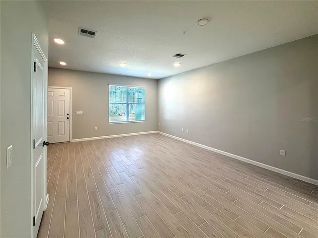an empty room with wooden floor and windows