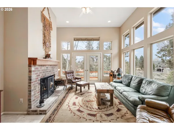 a living room with furniture a fireplace and floor to ceiling windows
