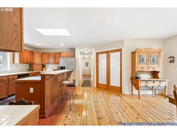 a open kitchen with stainless steel appliances granite countertop a refrigerator a sink dishwasher and a dining table with wooden cabinet