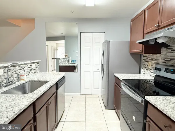 a kitchen with granite countertop a sink stove and refrigerator