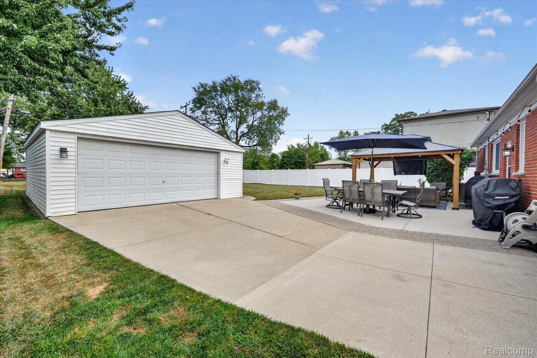 4112 Durham Road Royal Oak, MI 48073 - Photo 34 of 38 Detached white siding garage with a double door, expansive concrete driveway, and a concrete patio with paver accents