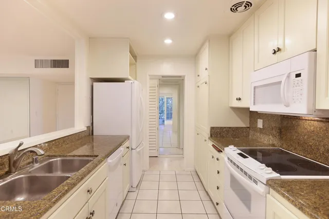 a large kitchen with granite countertop a sink and cabinets