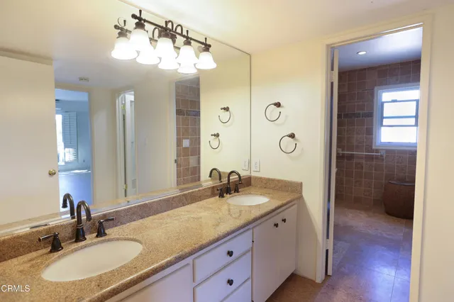 a bathroom with a granite countertop sink a mirror and shower