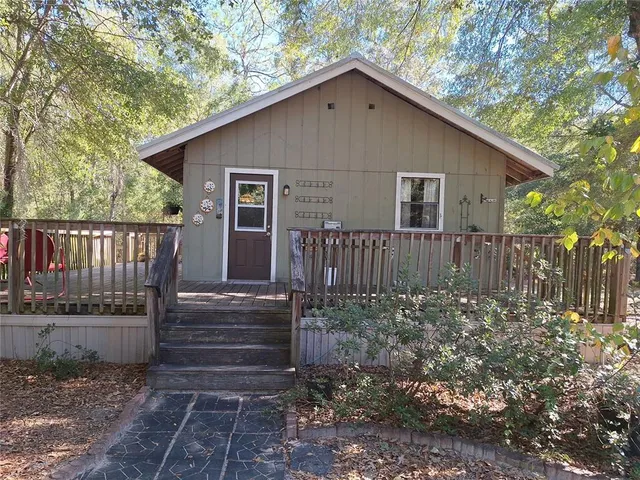 a view of a house with wooden fence next to a yard