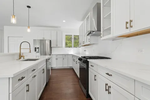 a kitchen with stainless steel appliances granite countertop a sink a stove a refrigerator and a oven with wooden floor