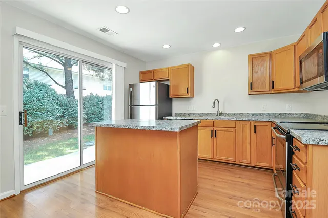 a kitchen with stainless steel appliances granite countertop wooden cabinets a sink and a large window