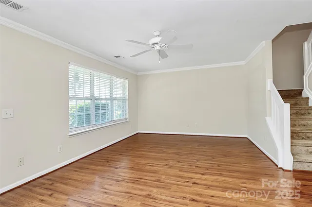 an empty room with wooden floor fan and windows