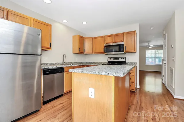 a kitchen with granite countertop a refrigerator and a stove top oven