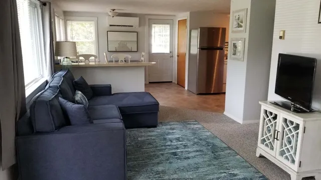 a living room with stainless steel appliances furniture and a flat screen tv