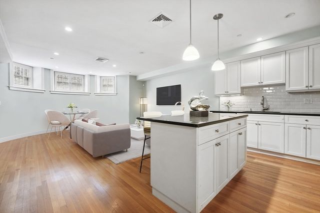 a kitchen with stainless steel appliances granite countertop a stove top oven a sink dishwasher and a refrigerator with wooden floor